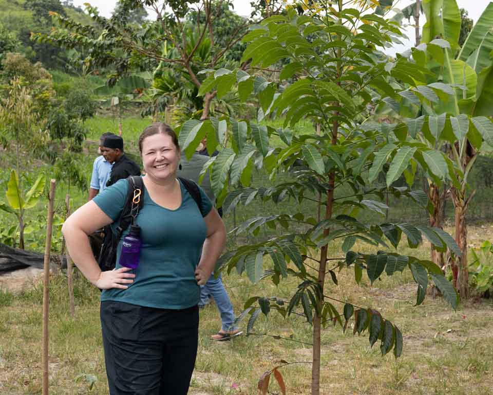 PUR Staff standing beside a one year old tree planted on a farmer's parcel.