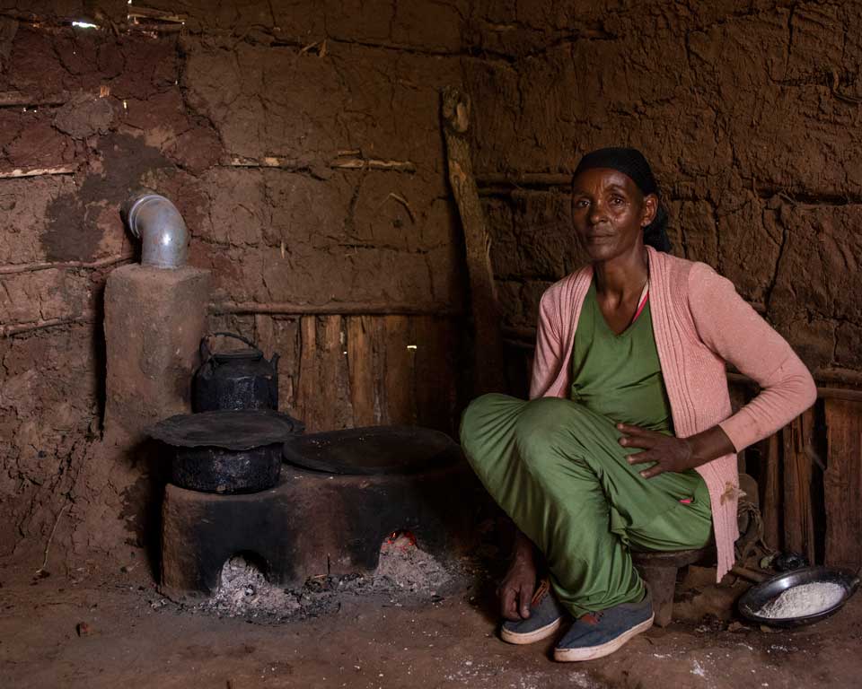 Une femme en Éthiopie assise à côté d'un fourneau amélioré.